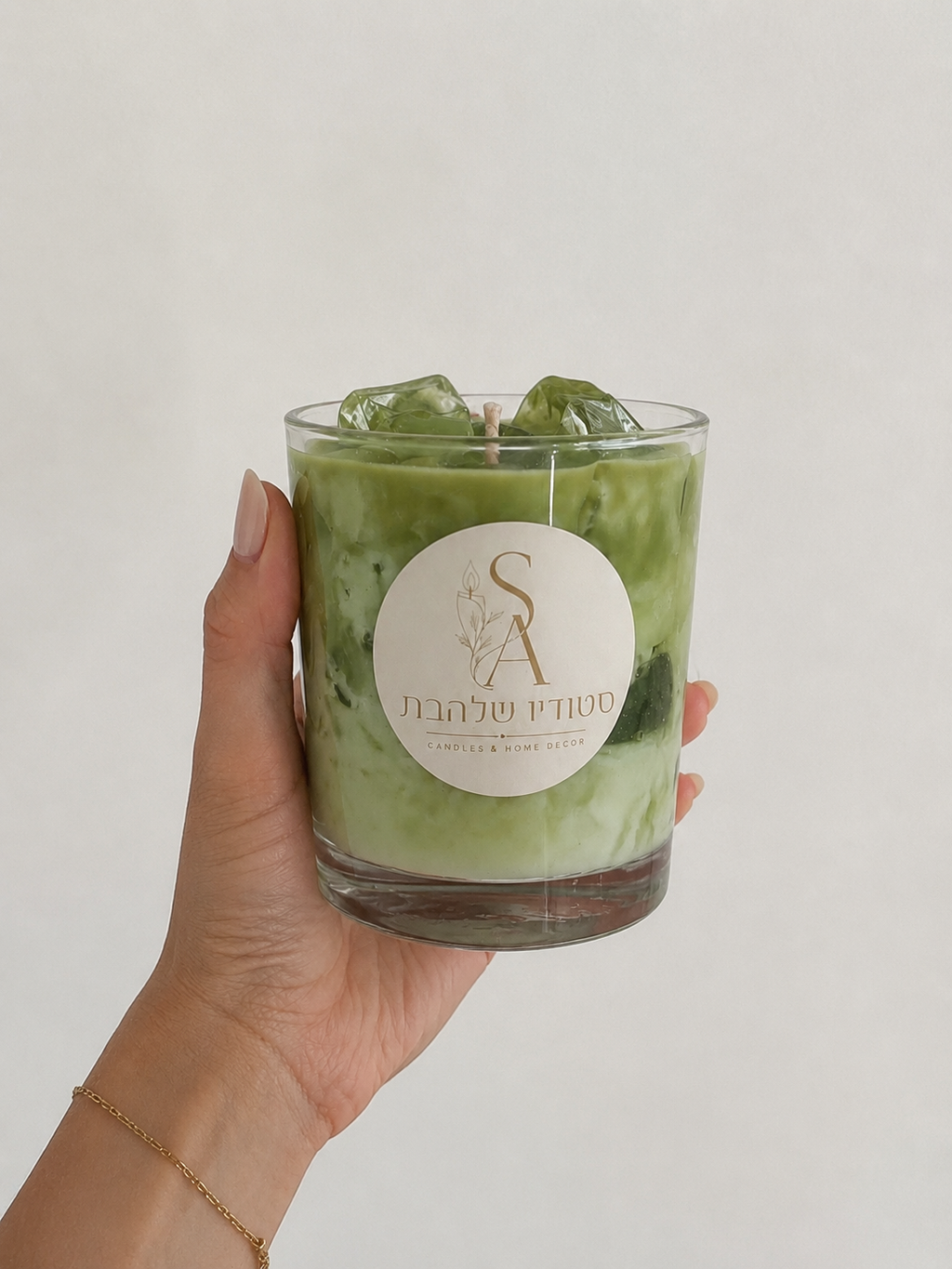 Matcha Latte – יד אוחזת את נר המאצ'ה הירוק בכלי זכוכית